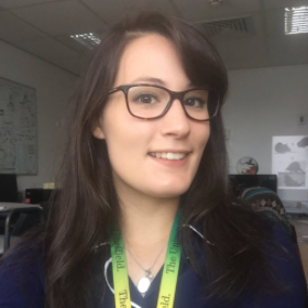 Dr Gaia Brezzo Profile Picture. Gaia is wering oval glasses she has long dark brown hair, and a green lanyard.