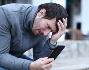 Man looking at his phone and holding his head