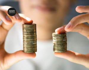 Person holding two stacks of £1 coins, one large and one small to demonstrate disparity on wages