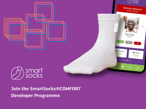 Promotional image for the SmartSocks COMFORT Developer Programme. A light grey sock with a small sensor is shown next to a smartphone displaying a care app alert reading Distress detected. The SmartSocks logo appears on a purple background with abstract square graphics and the text Join the SmartSocks COMFORT Developer Programme.