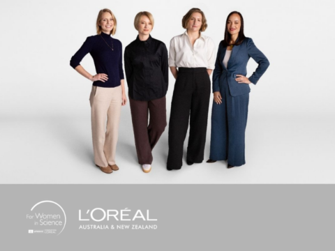 Four professionally dressed women stand side by side against a plain light background, smiling and facing forward. A banner below shows the For Women in Science logo and L’Oréal Australia and New Zealand branding.