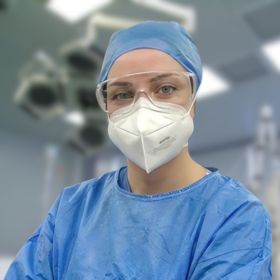 Dr Esra Demir Ünal - DEMENTIA RESEARCHER Surgeon or medical professional in blue scrubs, cap, and mask in an operating room.
