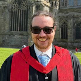 Smiling man wearing sunglasses on teal background, with Dementia Researcher logo and'Dr Connor McDonald' badge.